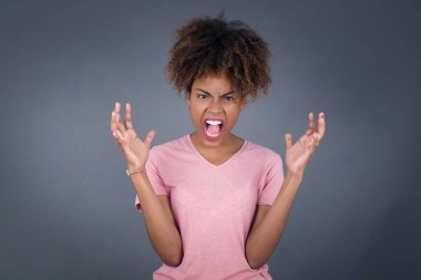 Çığlık, nefret, öfke. Kızgın, güzel, Afro-Amerikalı bir kadın mavi stüdyo arka planında çığlık atıyor. Duygusal, genç yüz. Yarım boy kadın portresi. İnsani duygular, yüz ifadesi kavramı. Moda renkleri