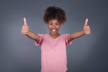 İyi iş! Genç ve güzel Afro-Amerikan kadın portresi. Kapalı alanda iki parmak hareketi yapıyor. Olumlu insani duygu yüz ifadesi vücut dili. Komik kız.