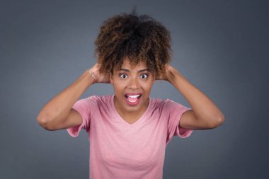 Heyecanlı genç Afro-Amerikan kadın iyi haberler aldıktan sonra çığlık atıyor, ellerini başının üstüne koyuyor, inanamıyorum..