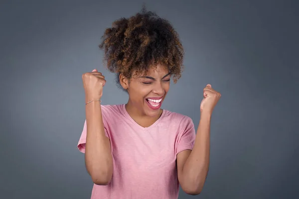 Caucasian brunette woman rejoicing her success and victory clenching her fists with joy. Lucky woman with hair bun being happy to achieve her aim and goals. Positive emotions, feelings.