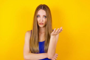 Hayal kırıklığına uğramış, sarı saçlı, avuçlarını kaldırmış, hayal kırıklığına uğramış ve kafası karışmış bir kadın.