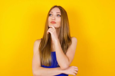 Düşünceli gülümseyen kızın portresi elini çenesinin altında tutuyor, yan bakıyor, ilgi çekici bir şey düşünüyor ya da merak ediyor.