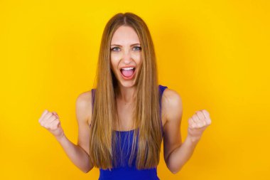 Beyaz kadın başarısını ve zaferini sevinçle kutluyor ve yumruklarını zevkle sıkıyor. Hedeflerine ve hedeflerine ulaşmaktan mutlu olan şanslı kadın. Olumlu duygular, duygular.