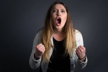 Güçlü, kararlı, sıradan kıyafetlerle, kollarını kaldırarak, yumruklarını sıkarak, sevinç ve heyecanla haykıran genç bir kadının portresi. Zafer, başarı ve başarı kavramı.