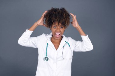 Güzel Afrikalı Amerikalı kadın doktorun portresi ellerini başının üstünde tutuyor. Güzel bir kadın ani haberlere tepki verir..