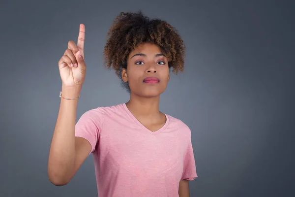 Jovem Afro Americana Contra Parede Cinza Apontando Para Cima Dedo — Fotografia de Stock