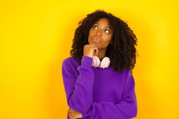 African american female in deep thinking process on yellow background. Emotions and gestures concept