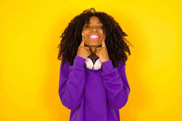 Mulher Afro Americana Sorri Segura Dedos Indicadores Suas Bochechas Fundo — Fotografia de Stock