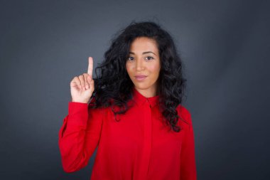 Kıvırcık saçlı, kırmızı tişörtlü, bir parmağını kaldırıp gülümseyen çekici genç esmer kadın. Bir fikrim var. Cevabı ya da çözümü biliyorum..