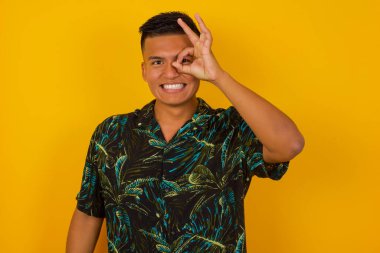 Gülümseyen, gülümseyen, el pençe divan duran yakışıklı, genç, İspanyol bir adam. Sıradan kıyafetler giyip ayakta durmak..