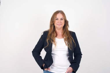 Güven ve iş kavramı. Çekici, orta yaşlı, beyaz bir kadının portresi. Gri duvarın önünde el ele tutuşurken kendinden emin bir ifadeyle gülümsüyor..