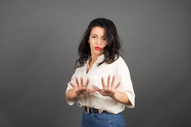 Güzel esmer kadın, günlük giyinmiş ve jest yapmamış. Gri arkaplanda duruyor. 