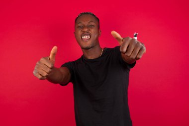 El ile pozitif jest yapıyor onaylama izole arka plan üzerinde genç Afro-Amerikan adam başparmak gülümseyen ve başarı için mutlu. Kamera, kazanan jest arıyorsunuz.