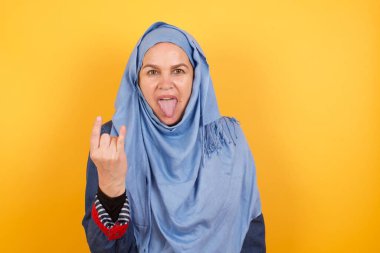 Orta yaşlı, tesettürlü çılgın bir müslüman kadının portresi. Dilini gösteriyor. Jest yapıyor..