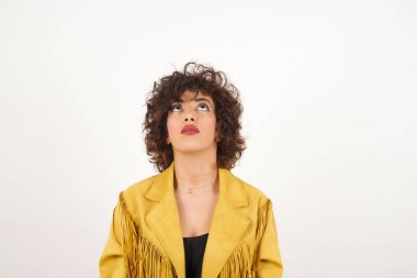 Süet ceketli güzel kadın stüdyo fotoğraflarına bakıyor.