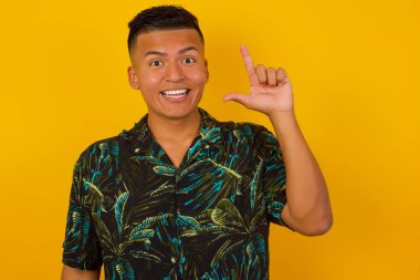 Hoş görünümlü İspanyol erkek modelinin yakın portresi zekice bir ifadeye sahiptir, parmağını kaldırır, önemli bir şeyi unutmaması gerektiğini hatırlar..