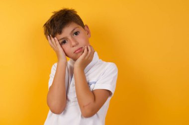 Yakışıklı çocuk sarı duvara karşı üzgün.  