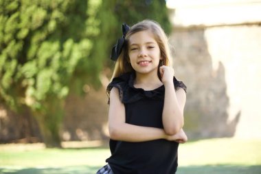 Yüzüne yakın eli olan siyah elbiseli neşeli, sevimli bir kız resmi. İyi haberleri dinledikten sonra kameraya mutlu bir ifadeyle bakmak. Kendine güvenen kız..