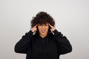 Genç ve güzel bir kız ciddi bir bakışla bir fikre odaklanıyor, iki işaret parmağı kapalı alnını işaret ederek düşünüyor..