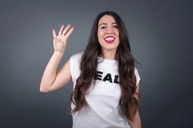 Gri arka planda dört parmak gösteren güzel bir kadın..  