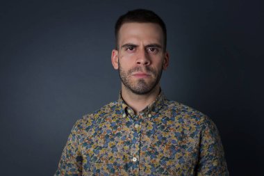 Oval yüzlü öfkeli bir gencin portresi, mavi gözlü, beyaz tişörtlü, kaşlarını çatan bir şeyden hoşnutsuz. Gri saçlı, güzel bir kadın..