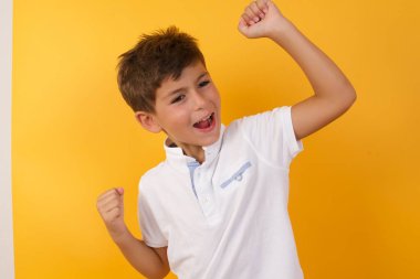 Sarı duvara karşı kutlama yapan sevimli çocuk.  