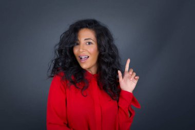 Kıvırcık saçlı, kırmızı tişörtlü, hoş görünümlü esmer kadının yakın portresi akıllı bir ifadeye sahiptir, bir parmağını kaldırır, önemli bir şeyi söylemeyi unutmaması gerektiğini hatırlar..