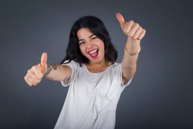 Soyutlanmış bir geçmişi olan genç bir kadın elleriyle olumlu jest yapmayı onaylıyor. Gülümsüyor ve başarı için seviniyor. Kameraya bak, kazanan jest..