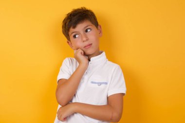Sarı duvara karşı düşünen tatlı çocuk.  