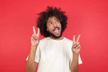 Kızıl duvara karşı zafer kazanan afro saçlı genç adam.   