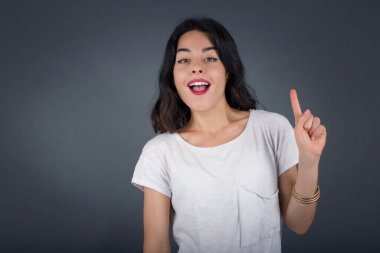 Hoş görünümlü genç bir kadının yakın portresi akıllı bir ifadeye sahiptir, bir parmağını kaldırır, önemli bir şeyi unutmaması gerektiğini hatırlar..