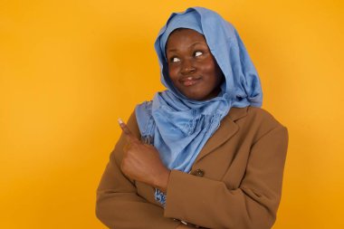 Güzel Afro-Amerikan Müslüman kadın kamerada poz veriyor, hileli bakışlar atıyor ve el kol hareketi yapıyor. Bayan tasarımcı, işaret parmağıyla harika bir ürün sunuyor. Hareket kavramı.