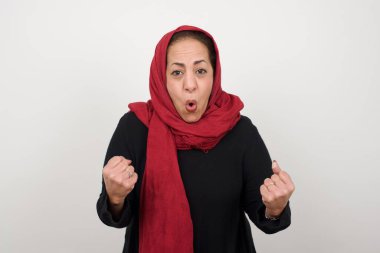 Başarılı, kararlı, tesettürlü, tesettürlü, kollarını kaldıran, yumruklarını sıkan, golü sevinç ve heyecanla haykıran olgun Müslüman kadının belden aşağı portresi. Zafer, başarı ve başarı kavramı.