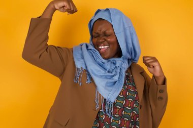 Evet, ben kazandım. Çekici, keyifli ve heyecanlı Afrikalı Amerikalı Müslüman kadının portresi zafer ve zaferle yumruğunu kaldırıyor mutluluktan sırıtarak başarı elde ediyor..