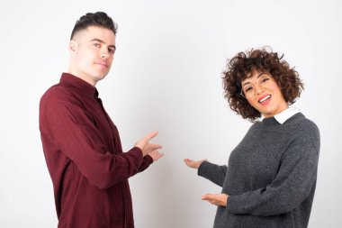 İzole edilmiş arka planda yaşayan genç ve güzel bir çift gülümseyerek doğal bir şekilde içeri girmeye davet ediyor. Hoş geldin işareti.