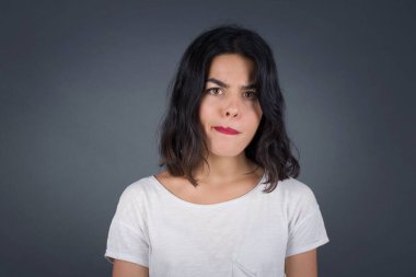 Düşüncelere dalan, kaşlarını kaldıran, dudaklarını kıvıran, şık kıyafetler giyen, metnin için fotokopi alanı olan gri duvara yaslanan düşünceli çekici bir kadın..