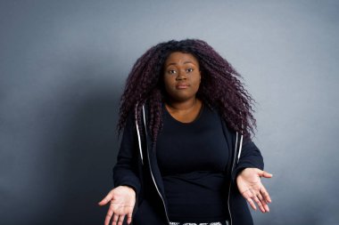 Kafası karışmış, kolları açık genç bir kadın omuzlarını silkip 