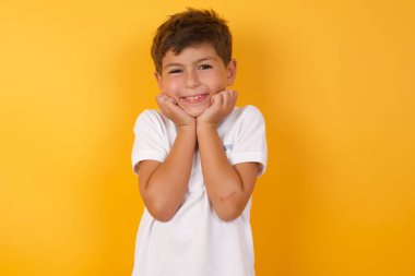 Sarı duvara gülümseyen sevimli çocuk.  