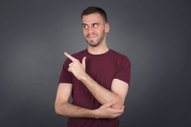 Kamerada poz veren genç bir adamın portresi hileli bir bakış ve yana hareket. Erkek tasarımcı güzel ürünleri işaret parmağıyla sunuyor. Hareket kavramı.