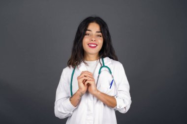 Tatlı yüzlü, rüya gibi genç bir doktor. Ellerini yüzünün yanında çapraz tutuyor. Hoş bir şey için heyecanlı..