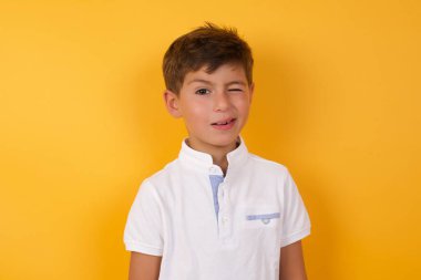 Sarı duvara göz kırpan sevimli çocuk.  
