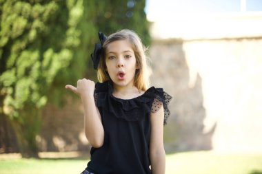 Genç ve neşeli bir kızın başparmağıyla işaret ettiği yatay görüntü bir şeyi işaret ediyor.