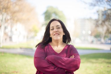 Parkta kollarını kavuşturmuş orta yaşlı güzel bir Arap kadın.  