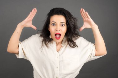 Gri arka planda gelişigüzel giyinmiş güzel esmer kadın..  