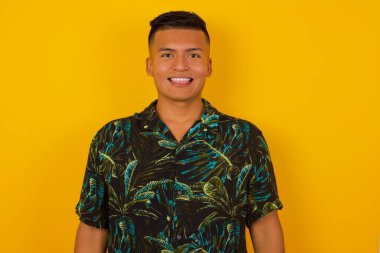 Mutlu ve komik yüzlü, gülümseyen ve dil gösteren güzel İspanyol bir adam. Günlük giysiler giyip stüdyonun arka planında dikiliyor..