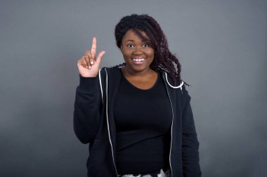 Hoş görünümlü Afro-Amerikan kadınının yakın portresi. Sıradan giyinmiş, akıllı bir ifadesi var. Bir parmağını kaldırıyor ve önemli şeyleri söylemeyi unutmaması gerektiğini hatırlıyor. Kapalı