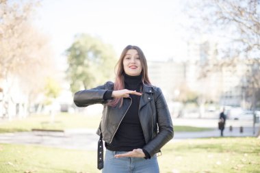 Genç ve güzel bir kadın parkta bir şey gösteriyor.