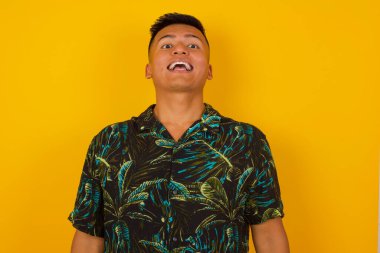 İnsanlar ve ani tepki kavramı. Şaşırmış İspanyol yakışıklı erkek, omuz silkiyor, yana bakıyor, arkadaşlarıyla yeni planları için mutlu ve heyecanlı. Gri duvarda izole edilmiş..