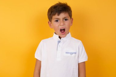 Sarı duvara karşı bağıran sevimli çocuk.  