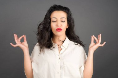 Gri arka planda meditasyon yapan güzel esmer kadın..  